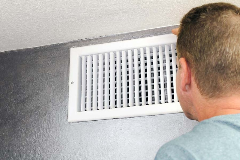 man in blue shirt looking at white air vent